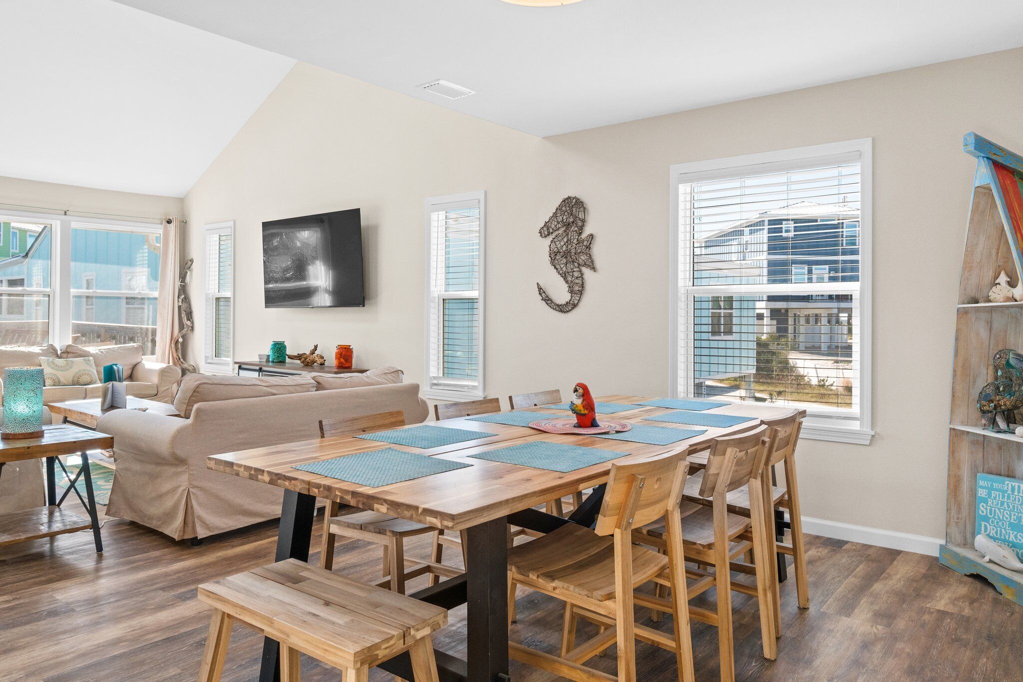 A dining area with a wooden table and chairs, a sofa, and a television on the wall.