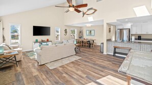 A spacious living area with a ceiling fan, a dining table, and a kitchen area with white cabinets. - 2 minute walk to the beach, stores and restaurants (Cape San Blas)