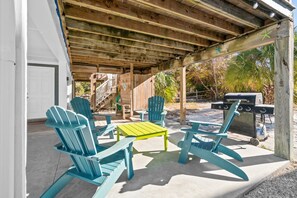 A covered patio area with blue Adirondack chairs, a yellow table, and a grill. - 2 minute walk to the beach, stores and restaurants (Cape San Blas)
