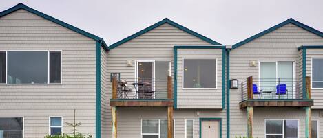 A row of townhouses with a balcony, a small garden area, and a metal bench.