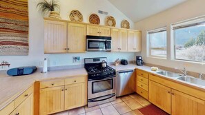 A modern kitchen with wooden cabinets, a gas stove, an oven, a microwave, and a dishwasher. - Desert Hideaway - C2, Enjoy The Views (Moab)