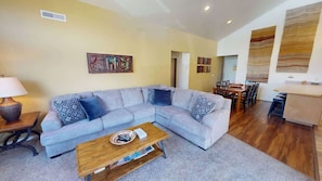Ein Wohnzimmer mit Sofa, Couchtisch und einem Essbereich mit Stühlen und Tisch.