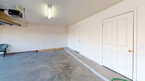 A clean, empty room with white walls, a door, and a ceiling-mounted projector.