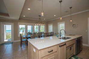 A spacious kitchen with a large island, overhead pendant lights, and a view of the ocean through the dining area. - Gulf Front, Pool & Elevator, 5bdrm (Indian Pass)
