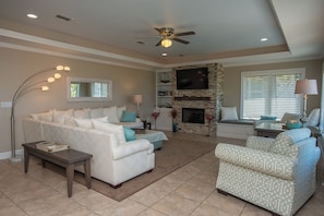 A living room with a white sofa, patterned armchair, and a fireplace. - Gulf Front, Pool & Elevator, 5bdrm (Indian Pass)