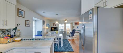 A modern kitchen with white cabinets, a stainless steel refrigerator, and a blue rug.