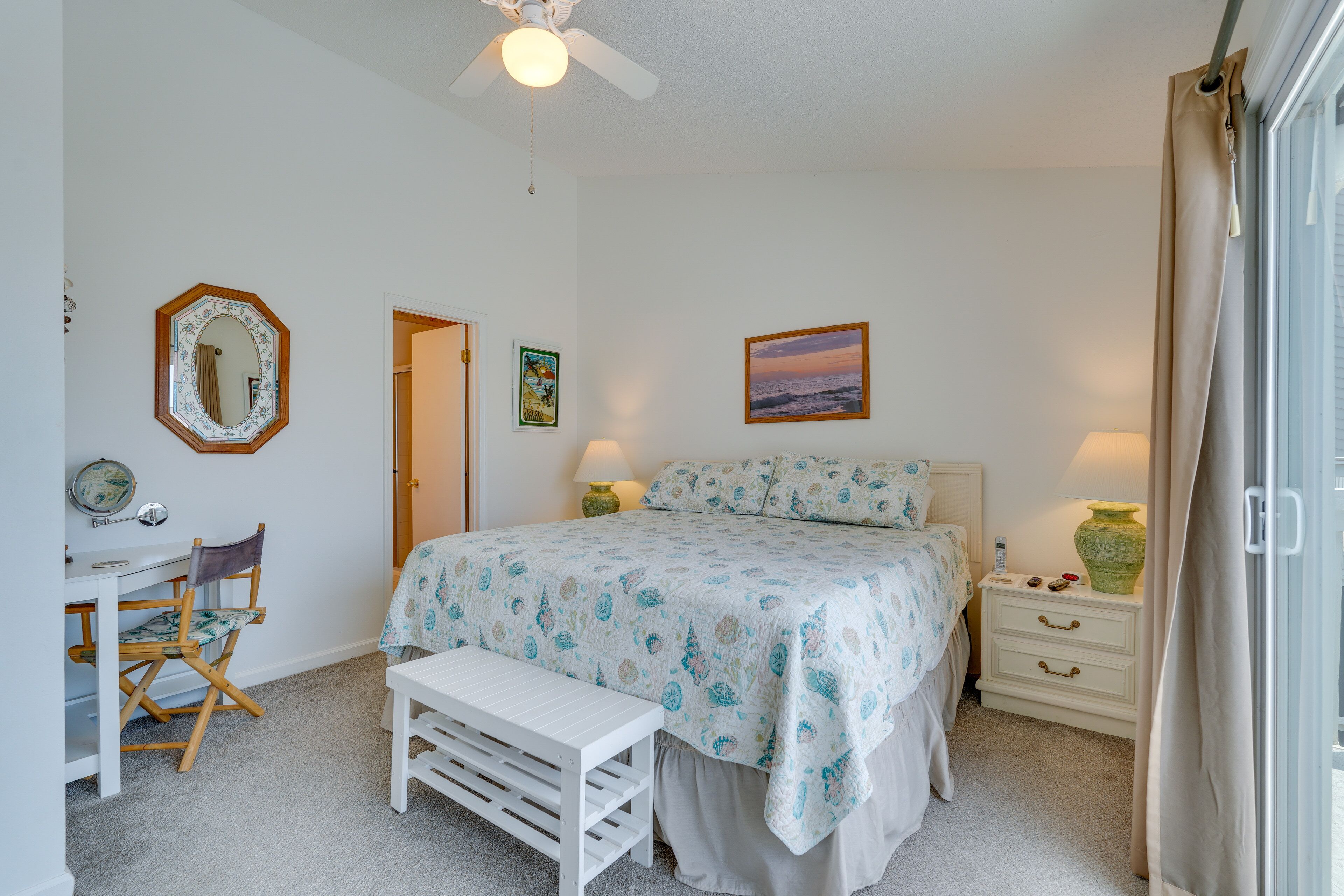 A bedroom with a bed, desk, chair, and a ceiling fan.