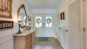 A hallway with a wooden cabinet, a mirror, and a door with a window.