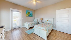 A bedroom with two beds, a ceiling fan, a painting, and a door. - Gulf Front! Elevator! Just steps to the ocean! (Cape San Blas)