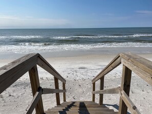 A wooden staircase leading to a beach with a view of the ocean.