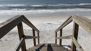 Eine Holztreppe führt zu einem Strand mit Blick aufs Meer.