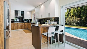 Una cucina moderna con isola centrale, mobili bianchi e vista su una piscina.