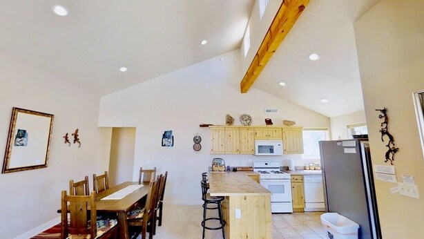 Una cocina con armarios de madera, una isla central con taburetes de bar y un refrigerador.