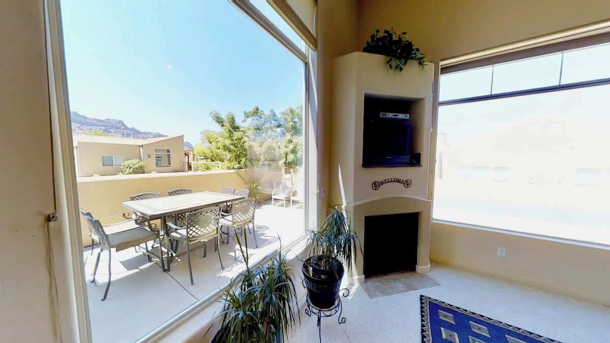 Een balkon met een tafel en stoelen, een aan de muur bevestigde televisie en een open haard.