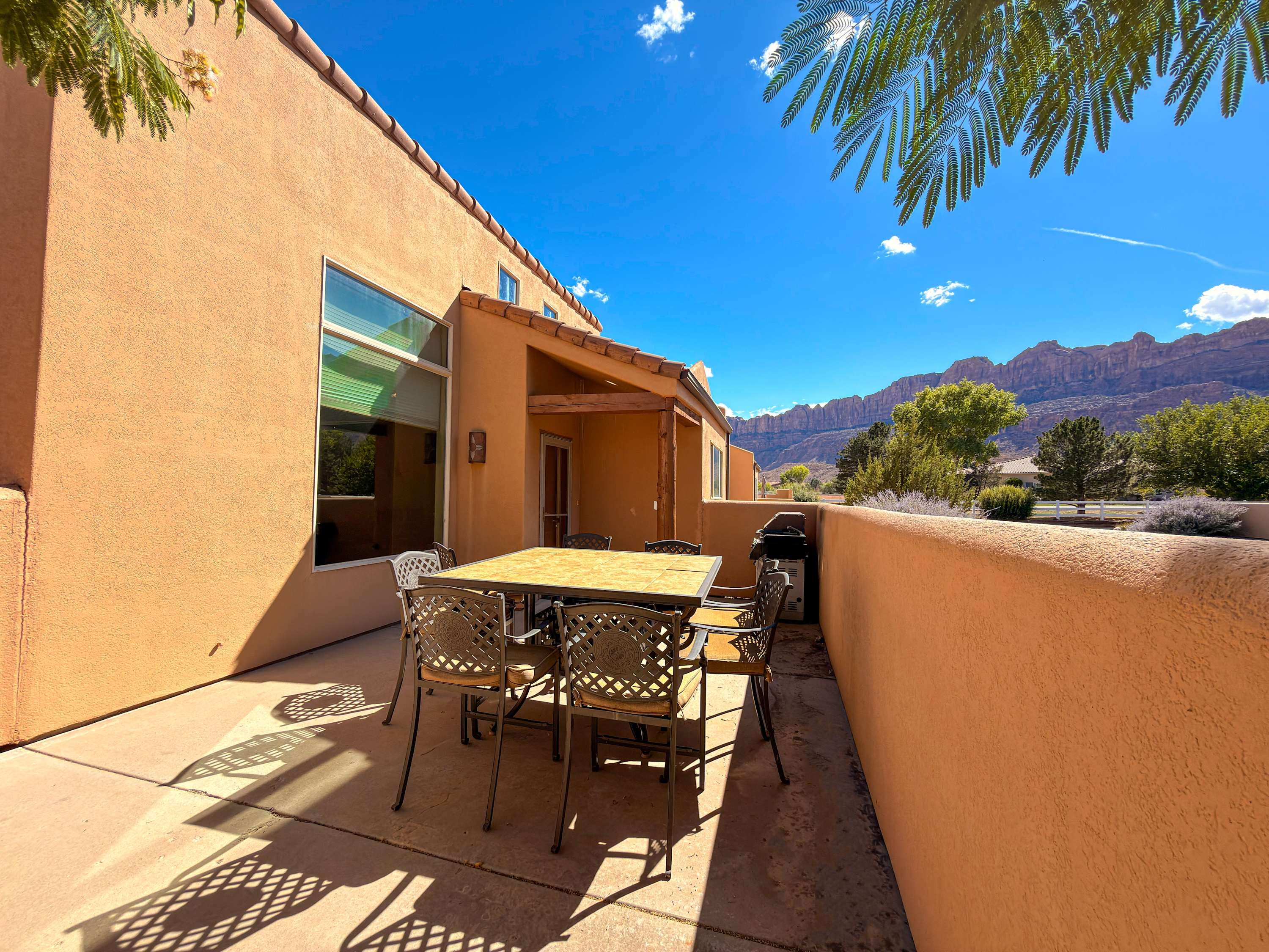 Une terrasse extérieure avec une table et des chaises, un barbecue et une vue sur les montagnes.