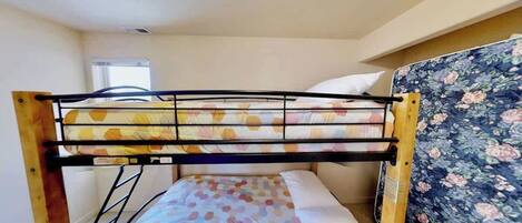 Un letto a castello con una testiera a motivi floreali e una finestra sullo sfondo.