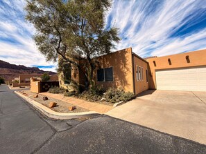 A residential property with a garage, a driveway, and a landscaped front yard with rocks and shrubs.