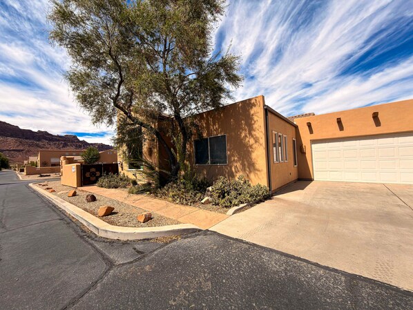 A residential property with a garage, a driveway, and a landscaped front yard with rocks and shrubs.