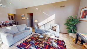 A living room with two sofas, a coffee table, and a patterned rug.