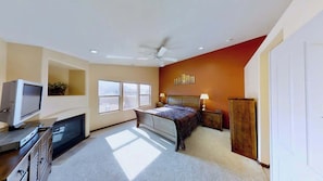 A bedroom with a bed, a television, a desk, and a wardrobe.