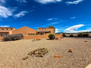 A desert-style building with a gravel driveway and sparse vegetation.