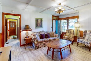Cozy living room with a floral-patterned sofa set, wooden coffee table, and armchairs.