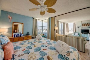 Une chambre d’hôtel avec un lit, une télévision, un canapé et une grande fenêtre.