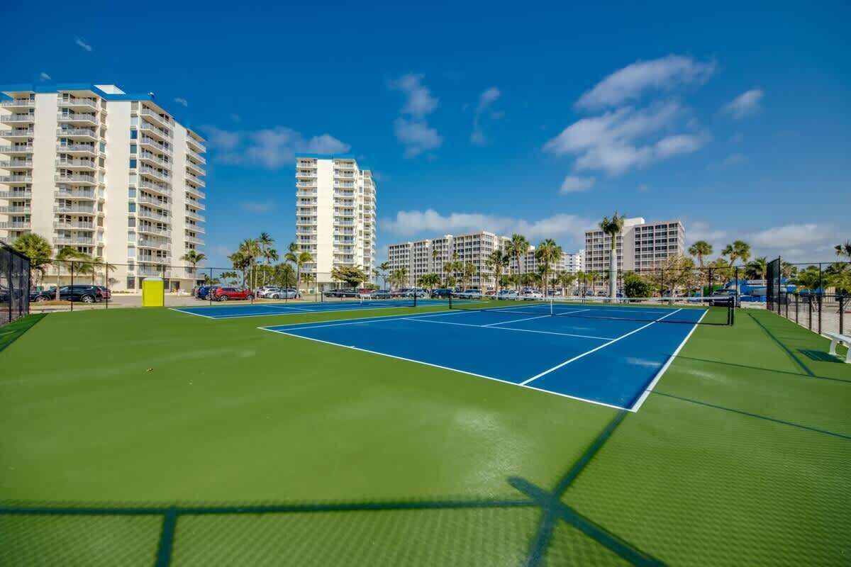 Un court de tennis entouré de bâtiments et de palmiers.