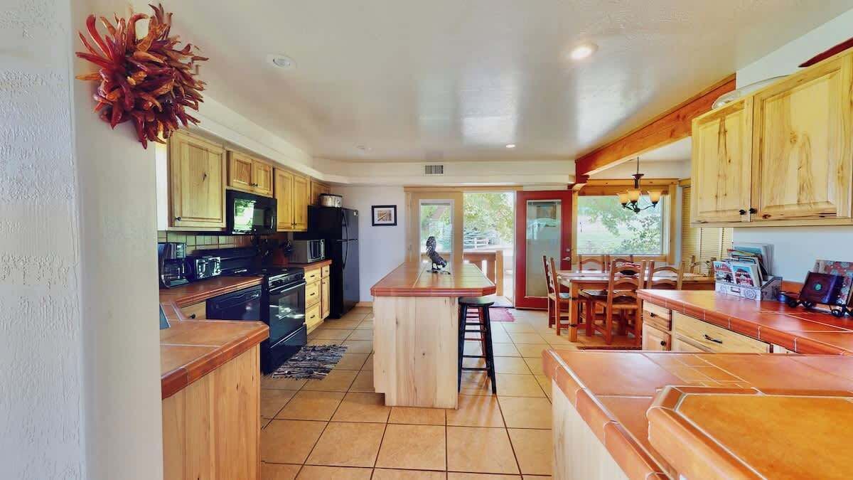 A kitchen with wooden cabinets, a central island, and a dining area with chairs.