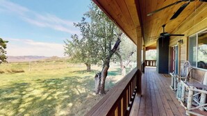 A wooden deck with a view of a grassy field and trees. - Pack Creek - Orchard House, Beautiful Cabin (Moab)