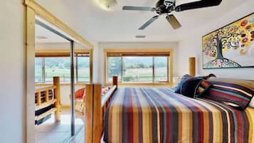 Un dormitorio con una cama grande, ventilador de techo y vistas al exterior a través de amplios ventanales.