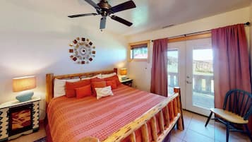 A bedroom with a bed, a ceiling fan, a wall clock, and a view through a door.