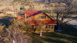 A wooden cabin with a red roof, surrounded by trees and mountains. - Pack Creek - Orchard House, Beautiful Cabin (Moab)