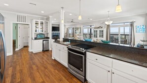 A spacious kitchen with white cabinetry, a large island, stainless steel appliances, and pendant lighting. - 5 Bedroom Beachfront (Cape San Blas)