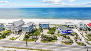 A beachfront property with multiple buildings, a road in the foreground, and a beach in the background.