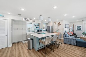 A modern kitchen with a central island, built-in appliances, and a dining area with wicker chairs.