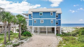 Ein zweistöckiges Strandhaus mit der Hausnummer 4047, einer überdachten Veranda und Blick auf den Ozean.