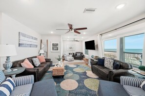 A modern living room with leather sofas, a coffee table, and a large window offering a view of the ocean. - Beach Front Home, Sleeps 9 (Cape San Blas)