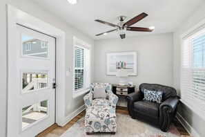 A living room with a ceiling fan, a sofa, a chair, and a rug.