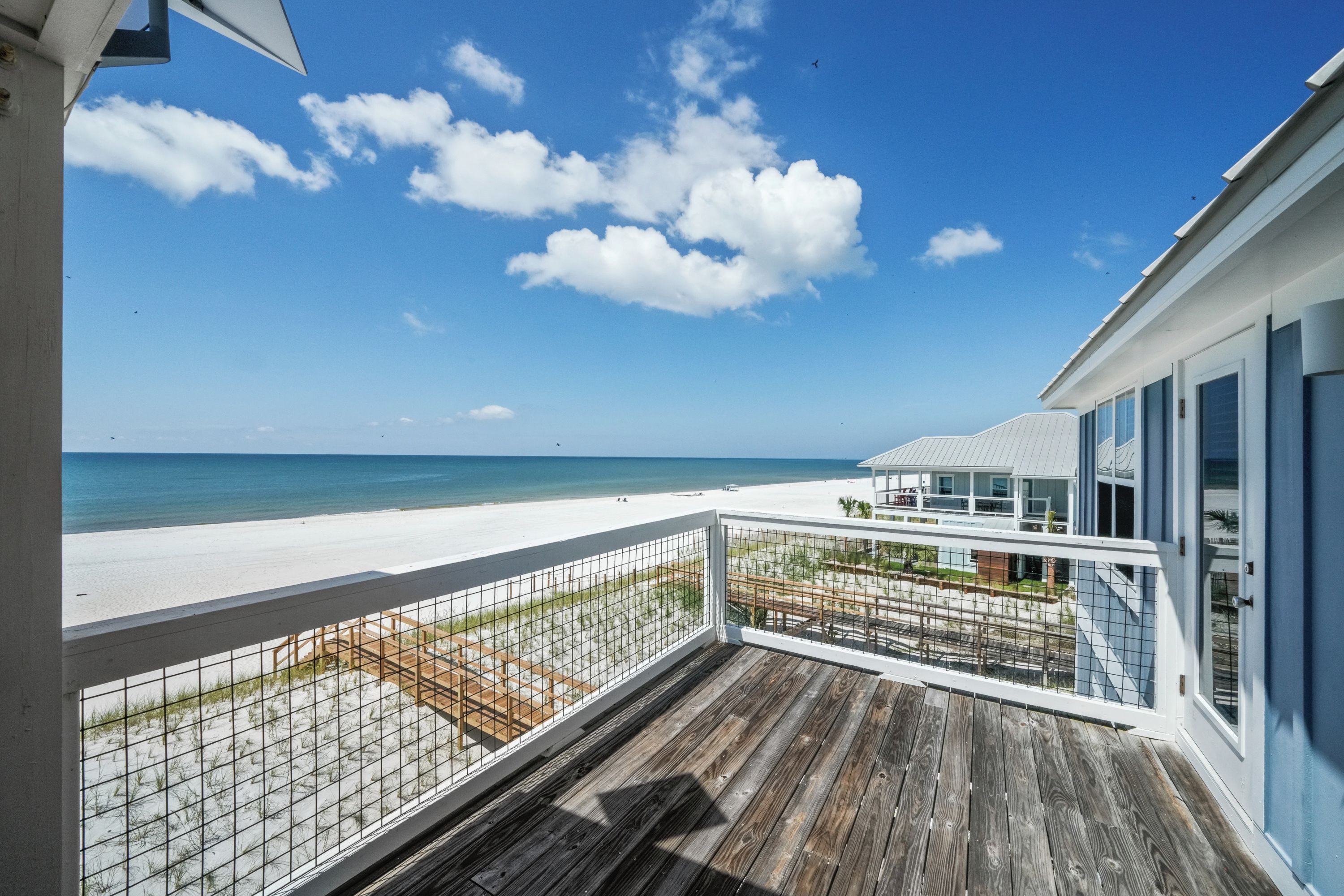 A wooden deck with a view of a beach and ocean.