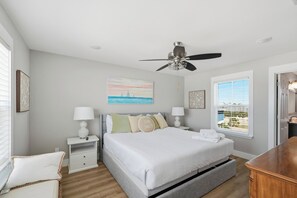 A bedroom with a bed, bedside tables, a ceiling fan, a window with a view, and artwork on the walls. - Beach Front Home, Sleeps 9 (Cape San Blas)