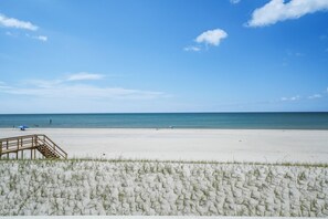 A beach with a wooden walkway leading to the water, a clear sky, and a calm sea. - Beach Front Home, Sleeps 9 (Cape San Blas)