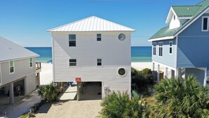 A beachfront house with a gable roof, a small porch, and a 'GLOST GETAWAY' sign. - Pet Friendly Beach Front Home (Cape San Blas)