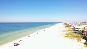 A beach with white sand, clear blue water, and a row of houses along the shore. - Pet Friendly Beach Front Home (Cape San Blas)