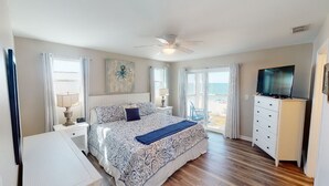 A bedroom with a bed, a TV, a dresser, and a view of the beach. - Pet Friendly Beach Front Home (Cape San Blas)