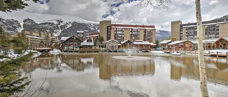 Ett hotell med flera byggnader, en central innergård med en fontän och snötäckta berg i bakgrunden.