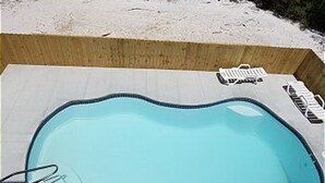 En lille, rektangulær swimmingpool med fliseterrasse, en badestige og en flydebolle.