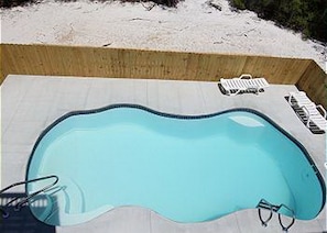 A small, rectangular swimming pool with a tiled deck, a pool ladder, and a pool noodle. - 1st Tier Home with Private Pool! (Cape San Blas)