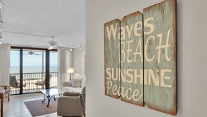 A room with a view of the beach, a ceiling fan, a sofa, and a coffee table.