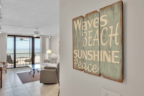 Quarto com vista para a praia, ventoinha no teto, sofá e mesa de centro.